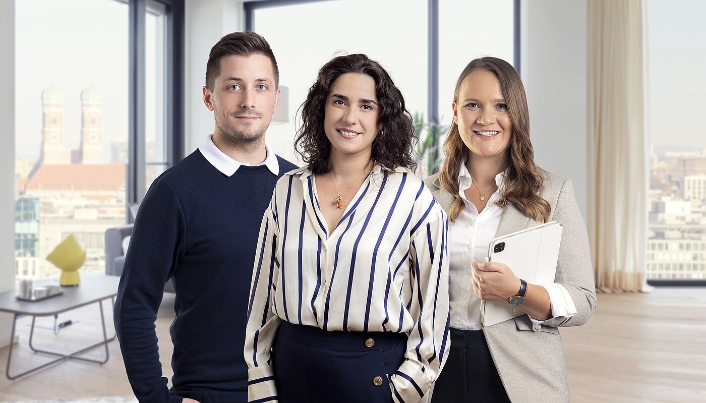 Die leitenden Mr. Lodge Mitarbeiter im Bereich Vermietung Felix Hensel, Doris Palmiero und Lisa Hessner vom Mr.Lodge Team in einem modern möblierten Apartment mit Blick auf die Münchner Frauenkirche – Experten für möblierte Vermietung und Immobilienverkauf in München.